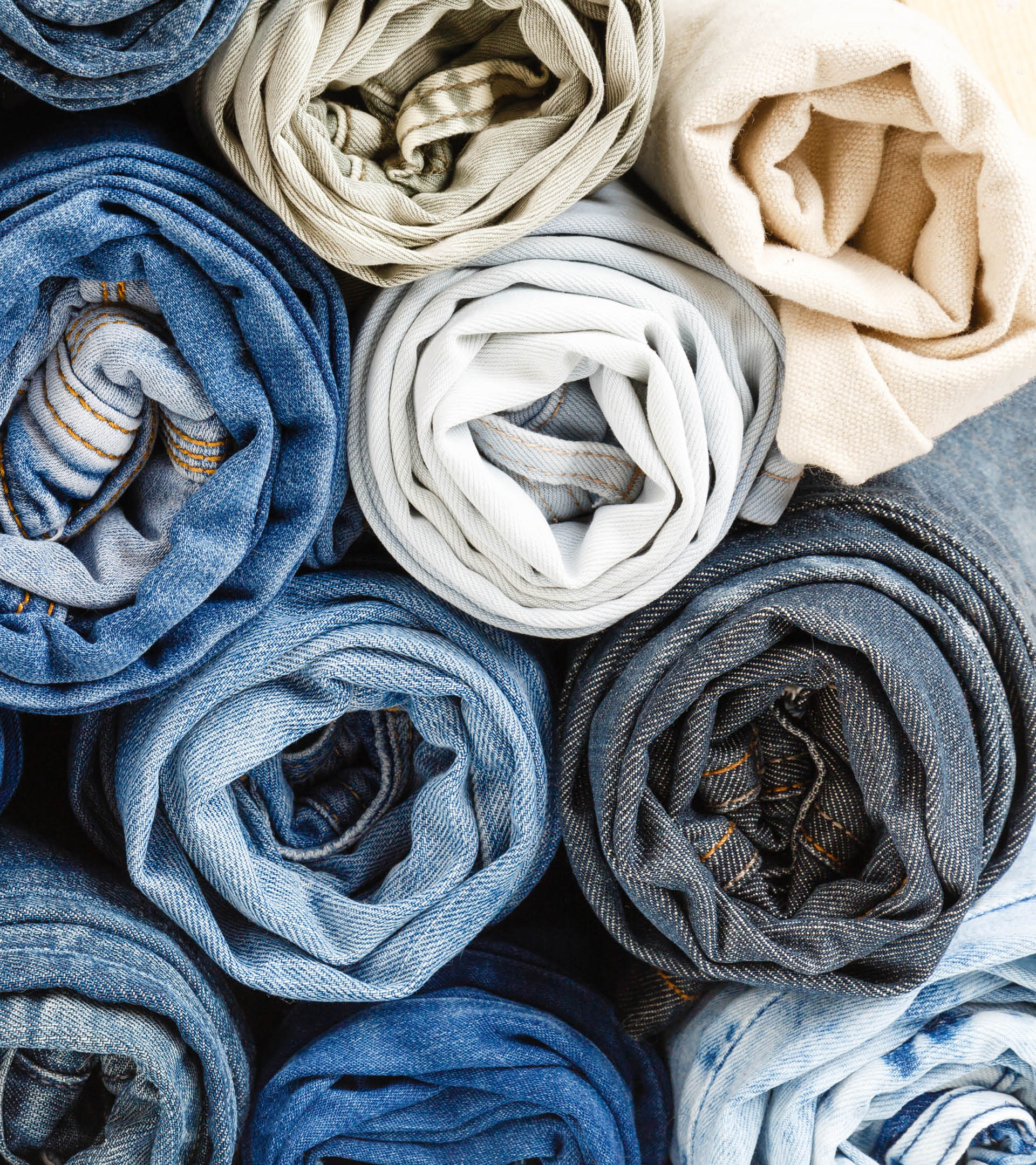 background from stack of different rolled jeans  Roll blue denim jeans arranged in stack  Jeans pyramid  Recycling old blue jeans on wooden table  Denim upcycle  Zero waste